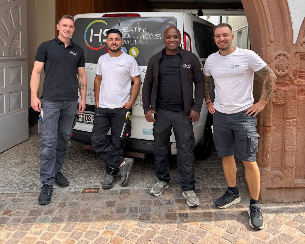 Vier Mitarbeiter von HS Heating Solutions vor dem beschrifteten Firmentransporter
